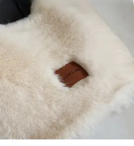 Close-up of fluffy plush fabric and brown leather brand patch on the beige tote bag