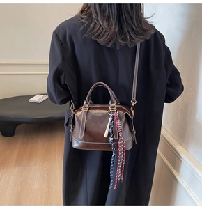 Dettaglio borsa Boston in pelle marrone scuro con cuciture bianche e tracolla regolabile
