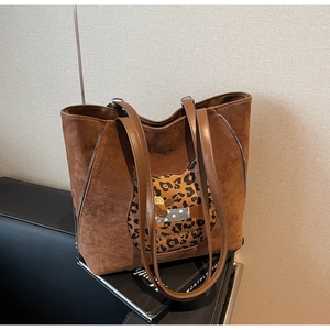 Detail of a brown suede tote bag featuring leopard print cat patch and embroidery