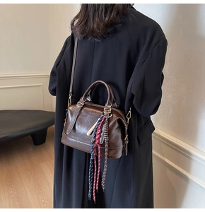 Dettaglio della borsa Boston vintage in pelle lucida marrone con nappine
