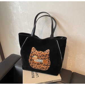 Detail of black suede tote bag featuring leopard cat patch and dachshund embroidery