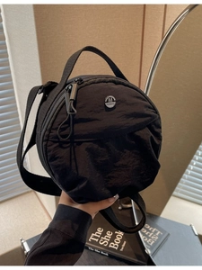 Sac à bandoulière rond noir en nylon avec logo M et bandoulière réglable pratique