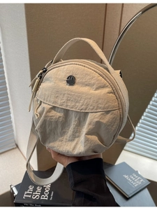 Petit sac rond beige en nylon avec double fermeture éclair et plaque logo M Fashion dorée