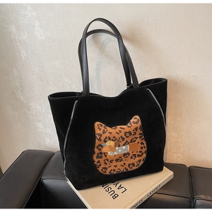 Detail of black suede tote bag with leopard cat patch and side zipper accents