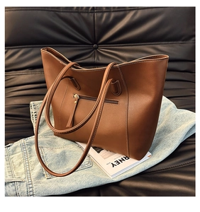 Close-up of a brown leather tote bag with metal zipper detail on lifestyle background