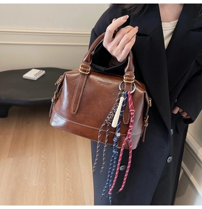 Dettaglio della borsa Boston vintage marrone scuro in pelle cerata con ciondolo