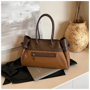 Close-up of a two-tone tote bag with a front zipper pocket and premium leather handles