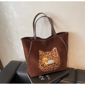 Detail of a brown suede tote bag with leopard cat patch and embroidered dachshund