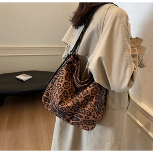 Detail of large leopard print tote bag with black slim straps worn with autumn trench coat