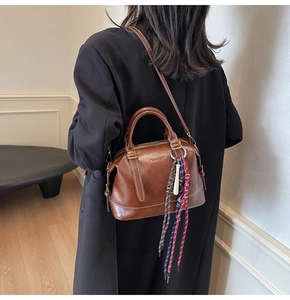 Dettaglio della borsa Boston vintage marrone con ciondolo intrecciato e cuciture bianche