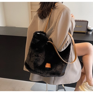 Detail of black faux fur tote bag with brown leather strap in a stylish autumn setting