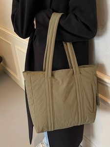 Quilted olive green tote bag for women shown with model for a casual winter look
