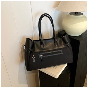 Detail of the black tote bag with dual-material texture and silver zipper accent