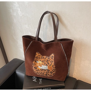 Close-up of brown suede tote bag featuring leopard cat patch and puppy embroidery detail
