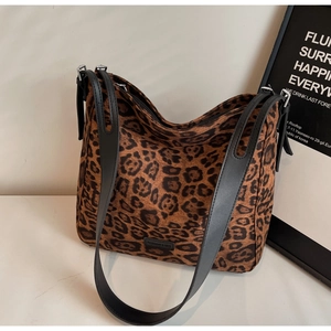 Macro detail of leopard print tote bag with black leather straps and metal zipper closure
