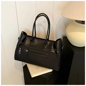 Close-up of a black tote bag showing smooth leather texture and front zipper detail