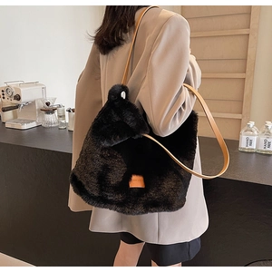 Macro view of large black plush tote bag with brown leather straps and square logo tag