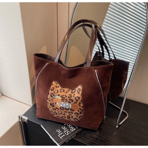 Detail of dark brown suede tote bag featuring leopard cat patch and cartoon embroidery