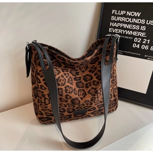 Close-up of leopard print tote bag fabric with fashion label and black leather straps