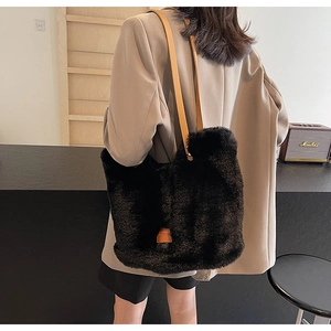 Detail of soft black faux fur tote bag with brown leather straps and branded side patch