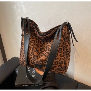 Close-up of leopard print tote bag with black leather straps and top zipper closure