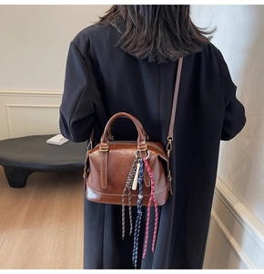 Dettaglio borsa a cuscino vintage in pelle marrone con ciondolo decorativo in corda