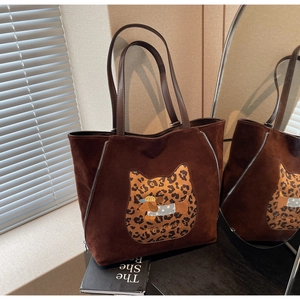 Detail of a brown suede tote bag featuring a cat-leopard patch and dachshund embroidery