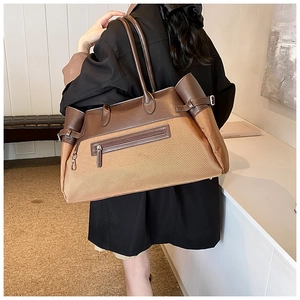 Detail of two-tone nylon tote bag featuring leather handles and functional zipper pocket