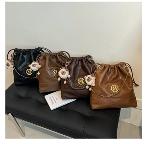 Close-up of four leather drawstring bucket bags in black, brown and caramel with M logo