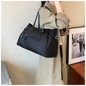 Detail of a large black nylon tote bag with leather trim and external zipper pocket