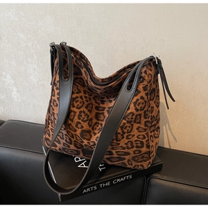 Detail view of large leopard print hobo bag with wide black leather straps on a sofa
