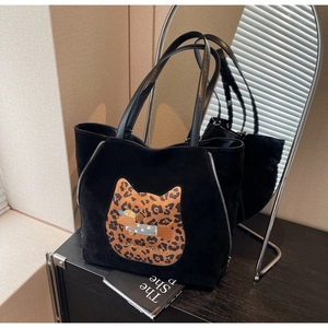 Detail of black suede tote bag featuring a leopard cat patch and dog embroidery