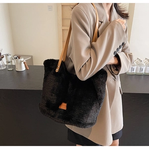 Close-up of black plush tote bag with brown leather straps in a lifestyle cafe setting