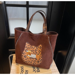 Detail of coffee brown suede tote bag with leopard cat patch and decorative zippers