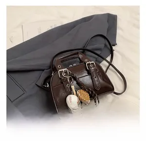 Détail du sac à main en cuir verni marron foncé avec charms baseball et boucles