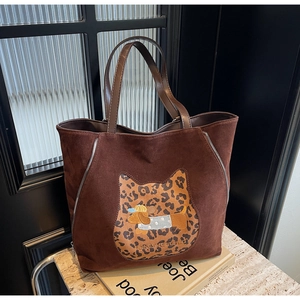 Detail of dark brown faux suede tote bag featuring animal embroidery and leopard patches