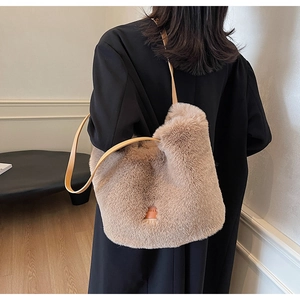 Detailed close-up of fluffy tote bag with leather strap on black coat outfit