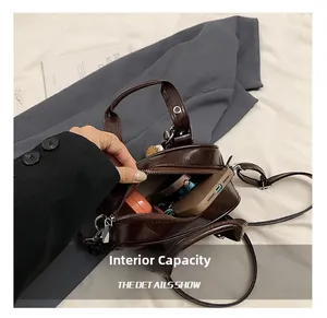 Détail de la capacité intérieure de ce sac à bandoulière en cuir brillant marron foncé