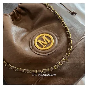 Detailed macro view of brown leather texture and golden M-logo on drawstring bucket bag