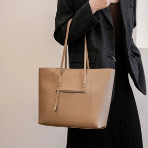 Detail of camel leather tote bag with long zipper pull and vertical stitching details
