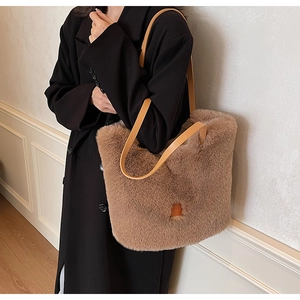 Close-up of fluffy brown plush tote bag featuring faux leather straps and brand patch
