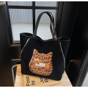 Detail of suede tote bag with leopard cat motif and dog embroidery on marble table