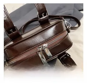 Détail du sac polochon en similicuir marron brillant avec double fermeture éclair en argent