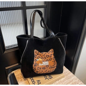 Macro shot of black faux suede tote bag with leopard cat patch and dog embroidery
