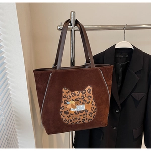 Close-up of a brown suede tote bag with cartoon puppy embroidery and leopard print detail