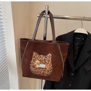 Detail of a brown suede tote bag featuring a cute dog patch and metal zipper accents