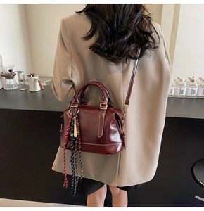 Dettaglio di borsa a mano vintage bordeaux con cinturino intrecciato laterale
