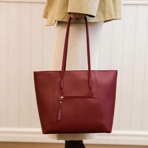 Detail of burgundy tote bag showing the back zipper pocket and high-quality leather texture