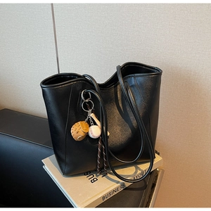 Detail of black faux leather tote bag with a sporty baseball glove and bat charm