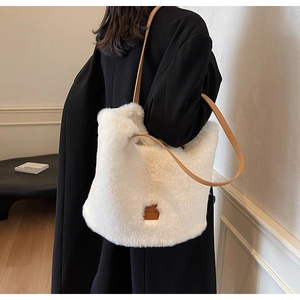 Detail of white faux fur tote bag with brown leather strap on a black coat outfit